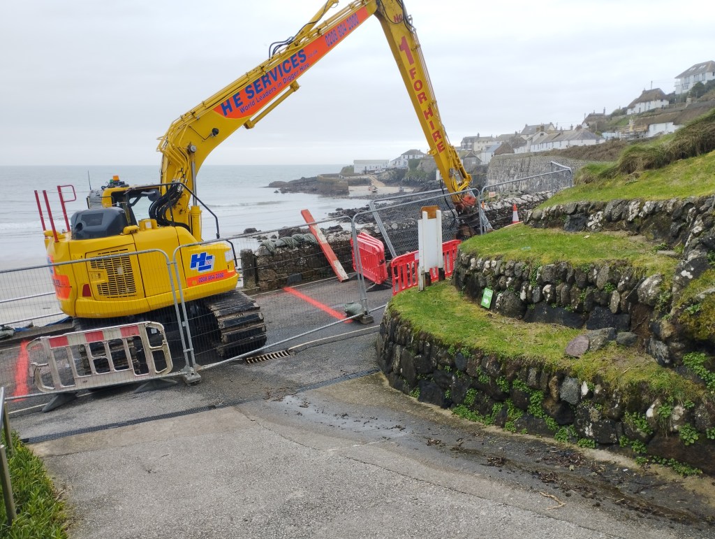 Digger above the hole in the sea wall
